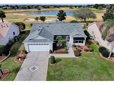 Charming home with landscaped front yard, driveway with decorative pattern, and golf course in the background at 1377 Eagle Ridge Dr, The Villages, FL 32162