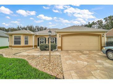 Charming one-story home with a two-car garage, decorative front door, and stone accents at 1732 Madero Dr, The Villages, FL 32159