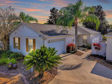 Charming one-story home showcasing lush landscaping, a driveway, and a white garage door at 2506 Greenhill Trl, The Villages, FL 32162