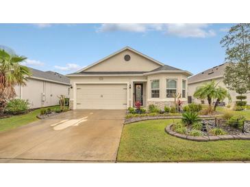 Charming single-story home with a two-car garage, stone accents, and well-manicured landscaping at 8677 Bridgeport Bay Cir, Mount Dora, FL 32757