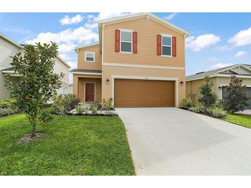 Charming two-story home featuring a brown two-car garage and beautifully landscaped front yard at 3040 Tansy St, Tavares, FL 32778