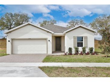 Charming single-story home with a brick driveway, well-manicured lawn, and neutral-toned facade at 1193 Stratton Ave, Groveland, FL 34736