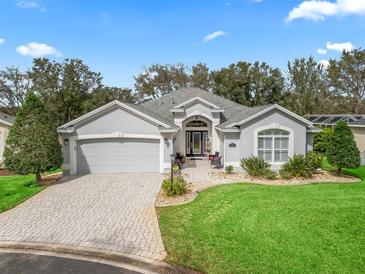 Charming one-story home showcasing a well-manicured lawn, brick driveway, and an attached two-car garage at 1415 Bethune Way, The Villages, FL 32162