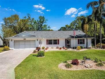 Charming single-story home with a well-manicured lawn, lovely landscaping, and an attached two-car garage at 27003 Racquet Cir, Leesburg, FL 34748
