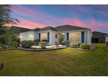 Charming single-story home with manicured lawn, lush landscaping, and a beautiful twilight sky at 3564 Nomad Ter, The Villages, FL 32163