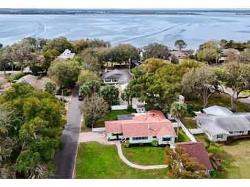 Aerial view of a beautiful home near the water surrounded by lush greenery and mature trees at 580 Page Ln, Mount Dora, FL 32757