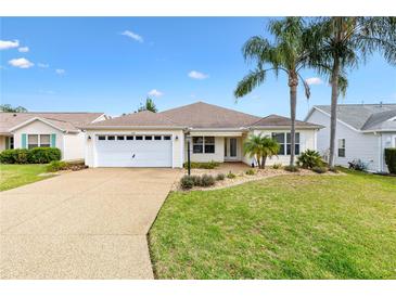 Charming single-story home featuring a well-manicured lawn and a two-car garage at 589 Sherwood St, The Villages, FL 32162