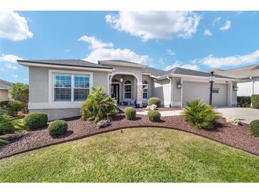 Charming single-story home featuring a manicured lawn, elegant landscaping, and a welcoming entrance with a well-maintained walkway at 686 Aberdeen Run, The Villages, FL 32162