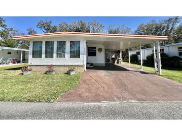 Charming home featuring a covered carport, well-maintained lawn, and neatly arranged flower pots at 104 Chestnut St, Leesburg, FL 34748