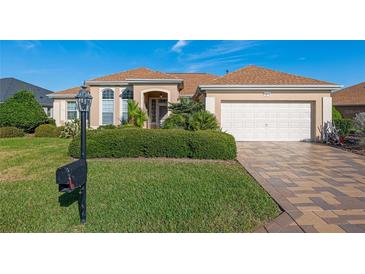 Charming single-story home featuring a well-manicured lawn, a two-car garage and tropical landscaping at 12239 Se 92Nd Court Rd, Summerfield, FL 34491