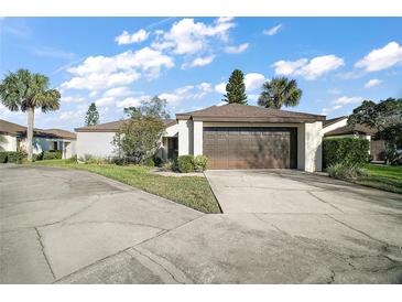 Charming single-story home featuring a two-car garage, well-maintained landscaping and a beautiful sky at 1945 Maple Cir # 45E, Tavares, FL 32778