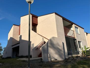 Exterior view of a two story condo with stairs and a balcony in a residential neighborhood on a clear sunny day at 2562 Lakeway Branch Way # 3002, Orlando, FL 32839