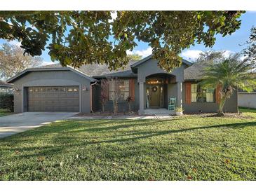 Charming single-story home with a well-manicured lawn, two car garage, and inviting front porch at 3130 Bulkley Pl, Eustis, FL 32726