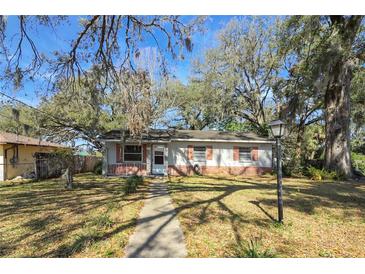 Charming single-story home with mature trees, manicured lawn, and inviting walkway at 6213 Highland Ave, Leesburg, FL 34748