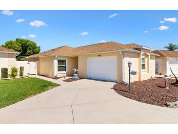 Charming single-story home featuring a well-manicured lawn, welcoming walkway, and attached garage at 1685 Garcia Ct, The Villages, FL 32159