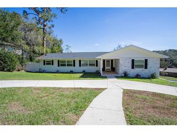 Charming single-story home with well-maintained lawn and a long driveway leading to a quaint covered entrance at 1930 Hilltop Dr, Mount Dora, FL 32757