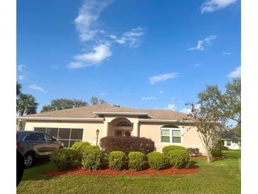 Charming single-story home boasts lush landscaping, arched entry, neutral stucco exterior, and attached garage at 21832 Prince William Ct, Leesburg, FL 34748