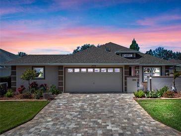 Charming home featuring a manicured lawn and paved driveway leading to an attached two-car garage at 21849 Tartan St, Leesburg, FL 34748