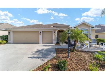 Charming single-story home featuring a three-car garage, a landscaped front yard and a welcoming front porch at 2279 Lowell Ter, The Villages, FL 32162