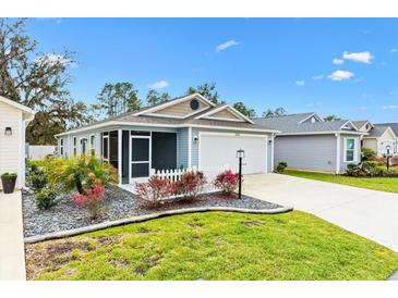 Charming single-story home with blue siding, manicured landscaping, and a white picket fence at 3320 Davis Ter, The Villages, FL 32163