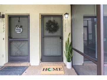 Inviting front entryway featuring a decorative wreath, welcome mat, and a well-lit entrance at 7266 Swallow Run # 7266, Winter Park, FL 32792