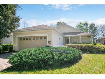 Charming single Gathering home featuring a two-car garage, mature landscaping, and neutral paint scheme at 112 Flame Vine Way, Groveland, FL 34736