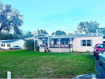 Charming single-story home featuring a covered porch, mature trees, and an expansive front yard at 11428 Pheasant Trl, Leesburg, FL 34788