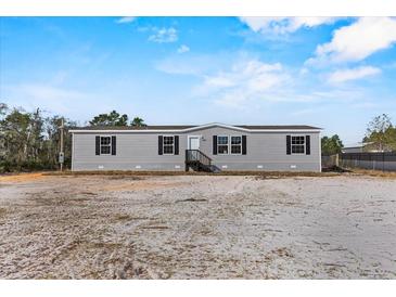 New construction home with gray siding, black shutters, and small front porch at 147 Woodstork Way, Frostproof, FL 33843