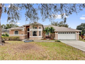 Charming, peach-colored two-story home with a two-car garage and mature landscaping at 1602 Oak Hollow Rd, Clermont, FL 34711