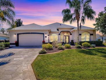 Charming single-story home featuring a well-manicured lawn and a two-car garage at 17694 Se 88Th Covington Cir, The Villages, FL 32162