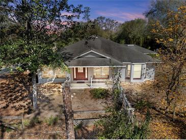 Charming single-story home featuring a landscaped front yard and cozy front porch at 25013 Adair Ave, Sorrento, FL 32776