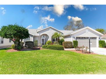 Charming single-story home featuring lush landscaping, a well-manicured lawn, and a two-car garage at 25265 Lost Oak Cir, Leesburg, FL 34748