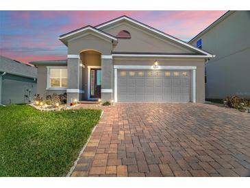 Charming home featuring a two-car garage, brick driveway, neutral paint, and well-maintained landscaping at 3139 Hurston Watch Ln, Clermont, FL 34711