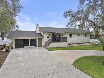 Charming single-story home with brick exterior, front porch, and a spacious driveway with attached garage at 31400 Saunders Dr, Tavares, FL 32778