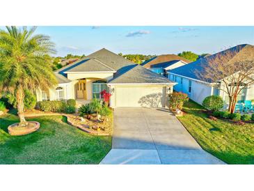 Charming single-story home featuring a well-manicured lawn, mature palm trees, and a two-car garage at 3144 Mayflower Loop, The Villages, FL 32163
