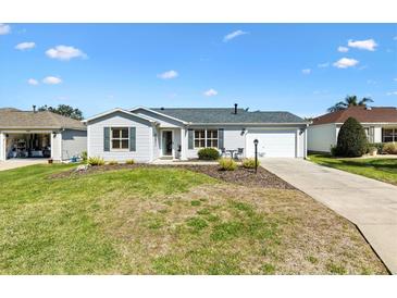 Charming single-story home featuring a well-manicured front yard with a cozy seating area and a driveway leading to the garage at 3349 Ashbrook Pl, The Villages, FL 32162