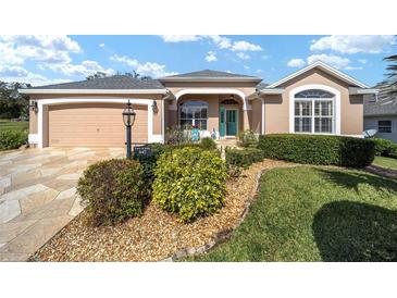 Charming home featuring a well-manicured lawn, beautiful landscaping, and a colorful front door at 447 Simpson St, The Villages, FL 32162