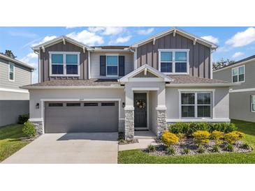 Charming two-story home with a well-manicured lawn and gray exterior with stone trim accents and a two car garage at 10177 Spring Lake Dr, Clermont, FL 34711