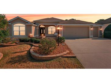 Charming single-story home featuring a well-maintained lawn, arched windows, and a two-car garage at 2311 Bramble Ter, The Villages, FL 32162