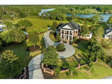 Stunning aerial view of a luxury home featuring a circular driveway, manicured lawn, and mature trees near a picturesque lake at 27852 Lake Jem Rd, Mount Dora, FL 32757