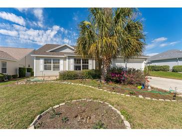 Charming single-story home featuring a well-manicured lawn and mature landscaping with a large palm tree at 3009 Batally Ct, The Villages, FL 32162