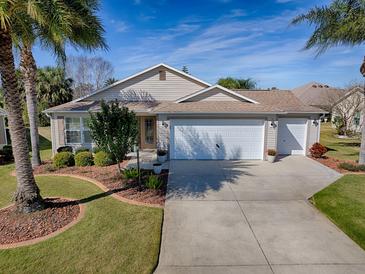 Charming single-story home with a well-manicured lawn, mature landscaping, and a spacious three-car garage at 3142 Islawild Way, The Villages, FL 32163