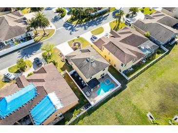 Aerial view of a yellow two-story home with a private backyard pool and fenced yard in a sunny neighborhood at 4982 Ne 124Th Rd, Oxford, FL 34484