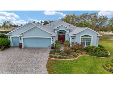 Charming single-story home with a well-manicured lawn, red door, and three-car garage, creating inviting curb appeal at 589 Society Hill Cir, The Villages, FL 32162