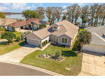 Inviting single-story home with a well-manicured lawn and an attached two-car garage near the lake at 6342 Sailboat Ave, Tavares, FL 32778