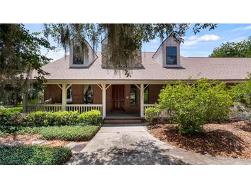 Charming brick home featuring a covered front porch and well-manicured landscaping at 10944 Autumn Ln, Clermont, FL 34711