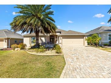 Charming single-story home with a paver driveway and lush landscaping, including a large palm tree at 1357 Owl Dr, The Villages, FL 32163