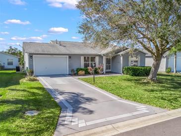 Charming home featuring a well-manicured lawn, decorative driveway, and a mature tree providing shade at 17442 Se 79Th Lovewood Ave, The Villages, FL 32162