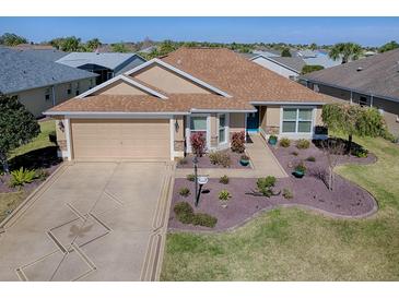 Stunning single-story home featuring a beautifully landscaped yard and a charming blue front door at 3330 Mayflower Loop, The Villages, FL 32163