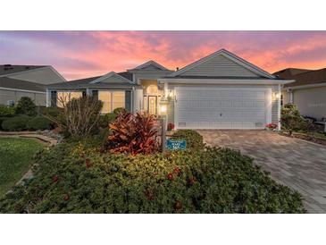 Charming single-story home with well-manicured landscaping, brick driveway, and attached two-car garage at 565 Brighton Dr, The Villages, FL 32162